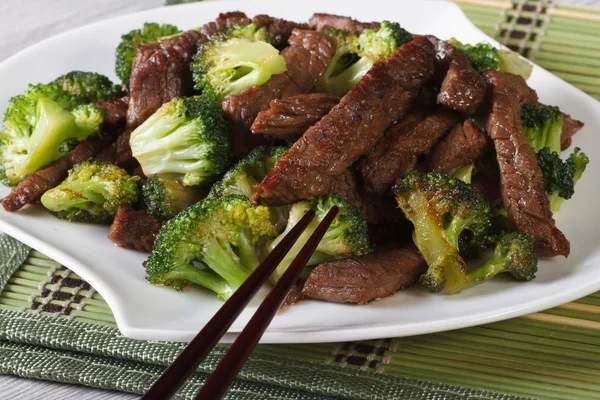 Pieces of beef with broccoli close-up and chopsticks. Horizontal — Stock Photo, Image