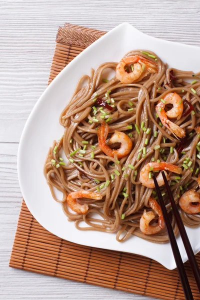 Soba-Nudeln mit Garnelen auf einem Teller aus nächster Nähe. vertikal — Stockfoto