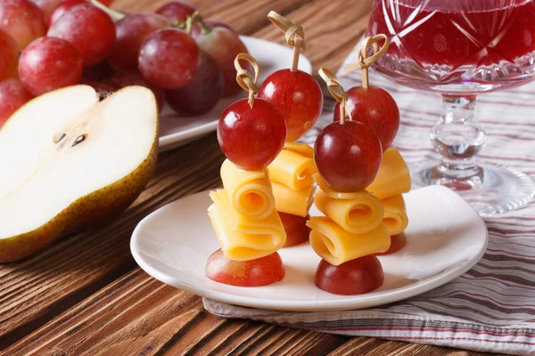 Uve rosse e formaggio sugli spiedini e un bicchiere di vino primo piano — Foto Stock