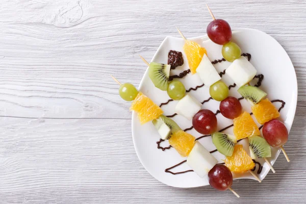 Tropische Früchte auf Spießen mit Schokolade. horizontale Ansicht von oben — Stockfoto