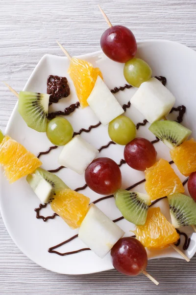 Grapes, kiwi, pear and orange on skewers vertical top view — Stock Photo, Image