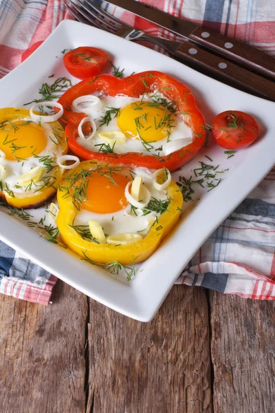 Fried eggs with peppers, tomatoes and onions close-up. Vertical — Stock Photo, Image