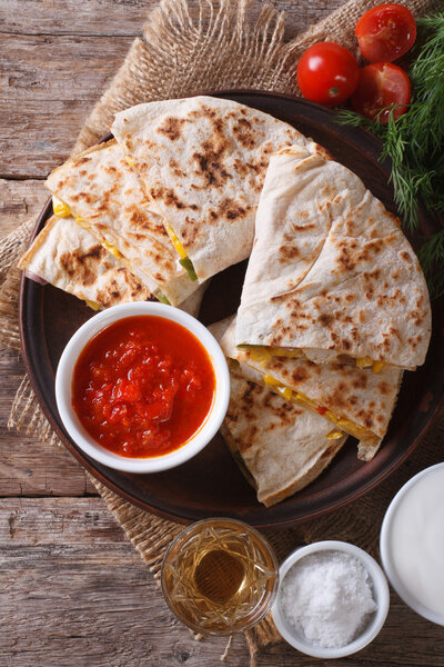 Quesadilla sliced and sauces on a plate close-up. vertical top v