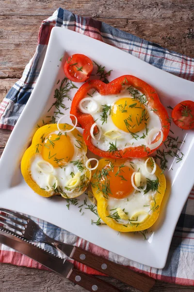 Fried eggs in yellow and red peppers close-up. vertical top view — Stock Photo, Image