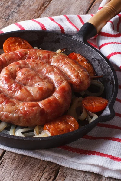 Salsiccia alla griglia con cipolle in una padella primo piano. Verticale — Foto Stock