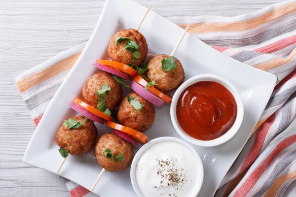 Meatballs on skewers with vegetables and sauce top view — Stock Photo, Image