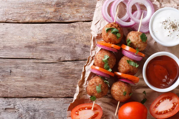 Meatballs on skewers and fresh vegetables top view, rustic — Stock Photo, Image