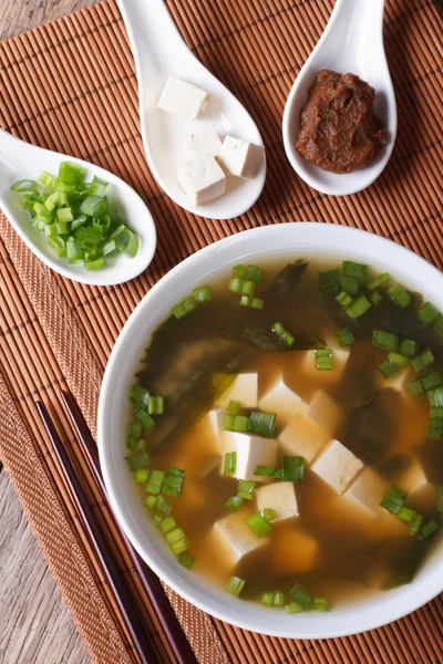 Miso soup in a white bowl and ingredients vertical top view — Stock Photo, Image