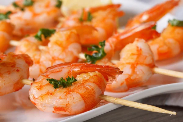 Delicious grilled shrimp on wooden skewers macro. Horizontal