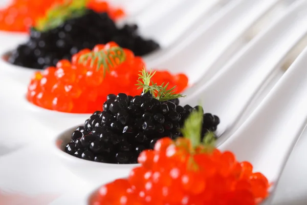 Delicioso caviar vermelho e preto closeup em colheres horizontais — Fotografia de Stock