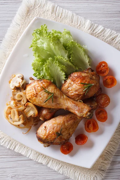 Fried chicken legs with mushrooms and tomatoes vertical top view — Stock Photo, Image