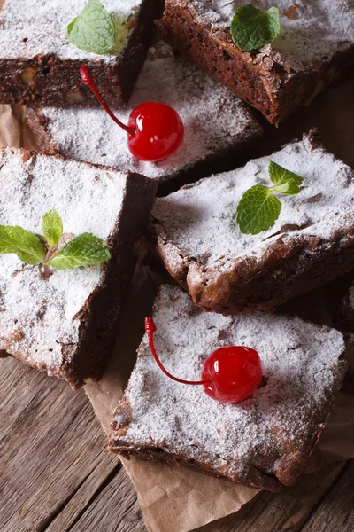 Chocolate cake brownies with mint and cherry closeup on paper — Stock Photo, Image