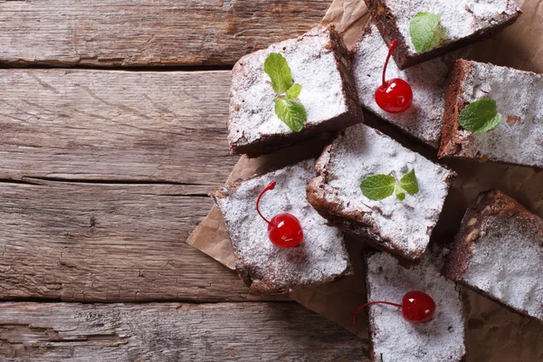 Brownie cake with mint and cherry on paper horizontal top view — Stock Photo, Image