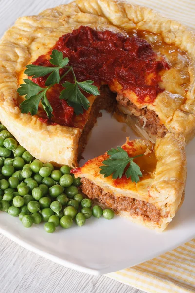 Fleischkuchen in Scheiben und grüne Erbsen. vertikale Nahaufnahme — Stockfoto