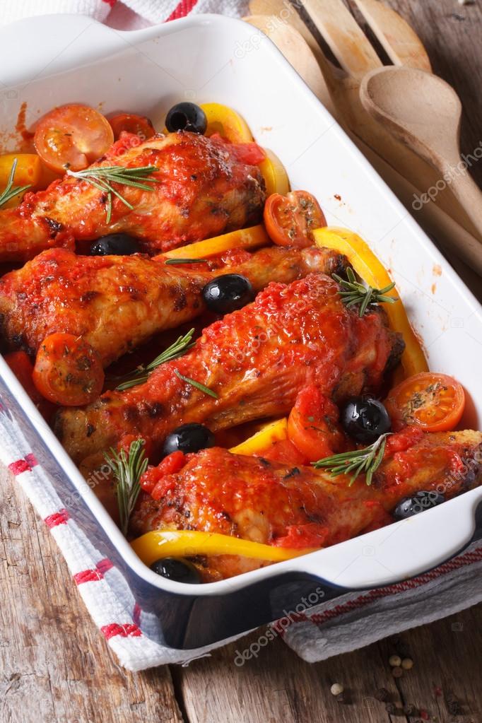 Chicken legs baked in tomato sauce with olives closeup. vertical