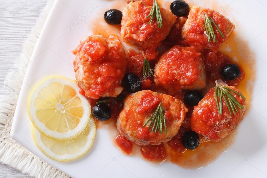  fish in tomato sauce on plate macro. horizontal top view closeu