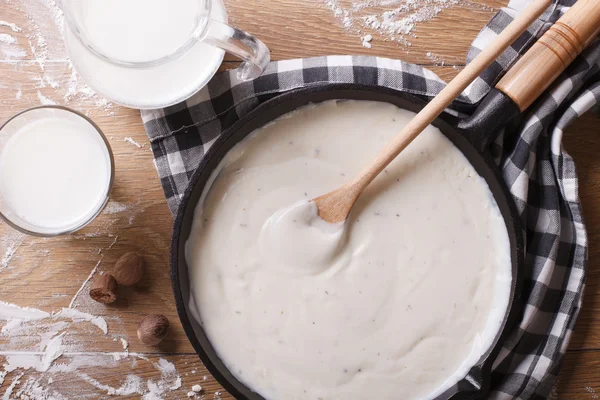 Salsa bechamel en una sartén y la leche en la mesa vista superior Imagen de archivo