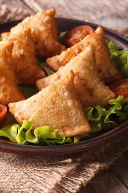 ahşap bir masa üzerinde marulla samosa. Dikey portre