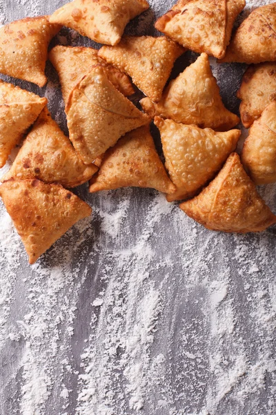 Un mucchio di samosa da forno su un tavolo infarinato. vista verticale dall'alto — Foto Stock