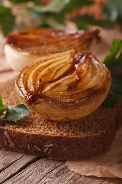 Sandwich with caramelized onions macro on an old table, vertical — Stock Photo, Image