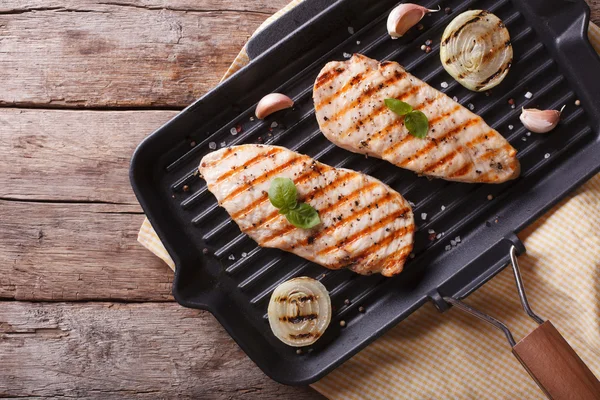 Kipfilet met ui in een pan-grill. horizontale bovenaanzicht — Stockfoto