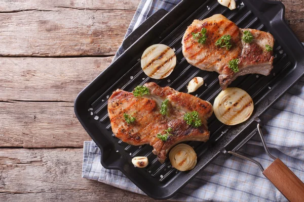 A hagymát egy serpenyőben grill, felülnézet vízszintes sertés szelet — Stock Fotó