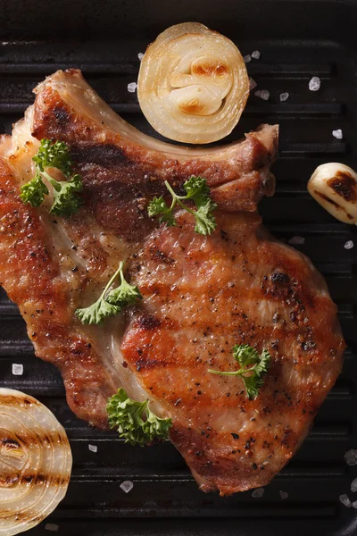 Schweinesteak mit Zwiebelmakro im Pfannengrill. vertikale Ansicht von oben — Stockfoto