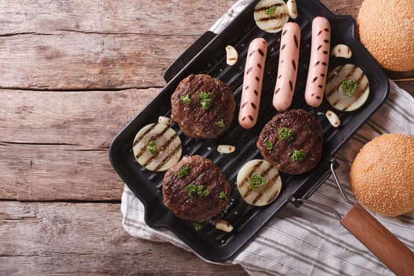 Burger und Würstchen auf einer horizontalen Grillpfanne — Stockfoto