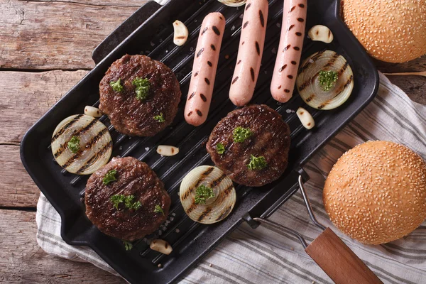 Burger und Würstchen auf einer Grillpfanne horizontal von oben Nahaufnahme — Stockfoto