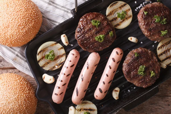 burgers and sausages on grill pan closeup. horizontal top view