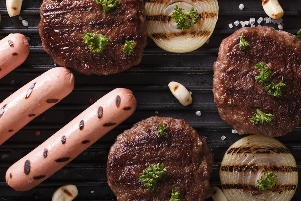 Hamburgers et saucisses aux légumes grillés macro vue dessus — Photo