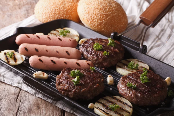 Hamburgers et saucisses aux légumes sur une poêle à griller, horizontale — Photo