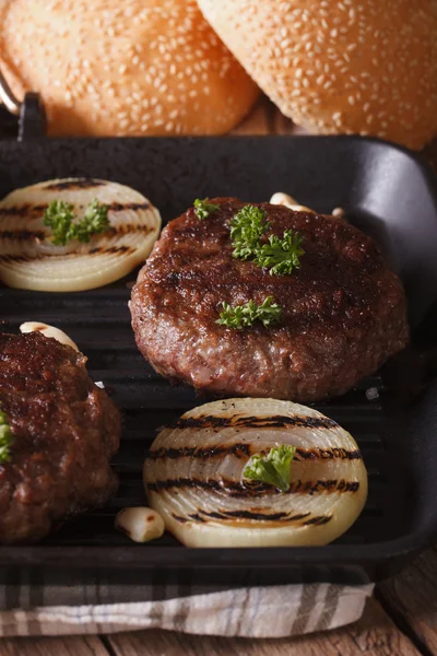 Hambúrgueres grelhados com cebola e alho na grelha. vertical — Fotografia de Stock