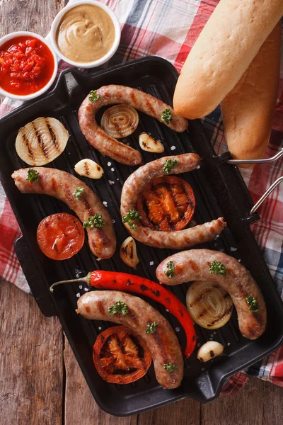 Sausages with vegetables on a grill closeup. vertical top view — Stock Photo, Image