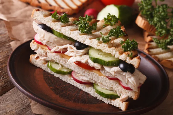 Сэндвич с курицей на тарелке и ингредиентами на столе — стоковое фото