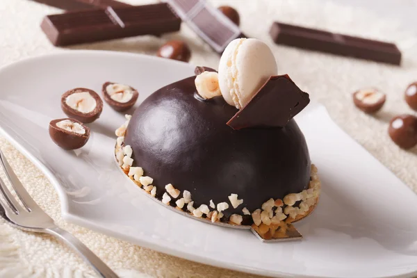 Delicious chocolate cake with nuts, topped with macaroon — Stock Photo, Image