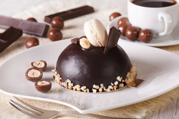 Chocolate cake with nuts, macaroon on a plate  and coffee — Stock Photo, Image