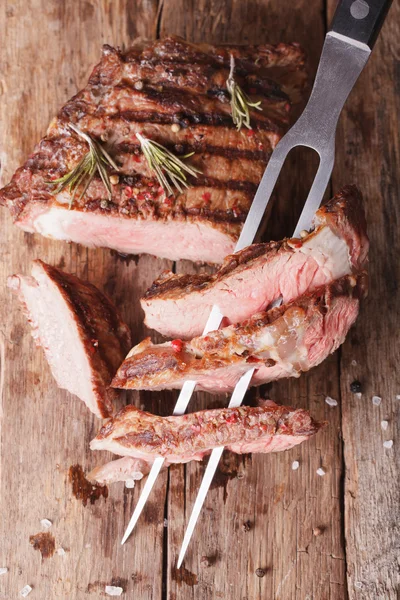Grilled beef steak with a fork for the meat. vertical top view — Stock Photo, Image