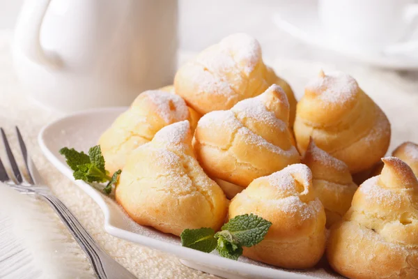 Profiteroles con azúcar en polvo de cerca, horizontales —  Fotos de Stock