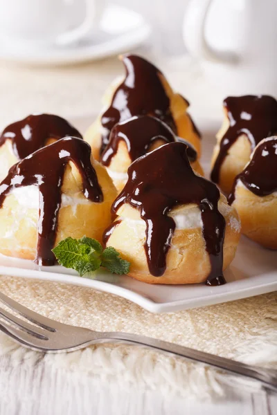 Profiteroles con crema y glaseado de chocolate en un plato. vertical —  Fotos de Stock