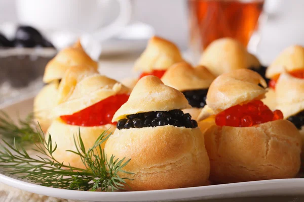 Tasty snack: profiteroles stuffed with red and black caviar