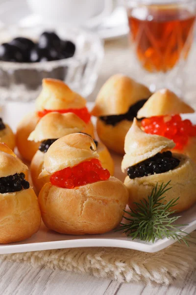 profiteroles stuffed with red and black caviar closeup. Vertical