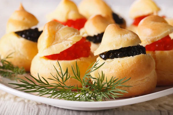 Comida para los dedos: profiteroles rellenos con caviar rojo y negro —  Fotos de Stock