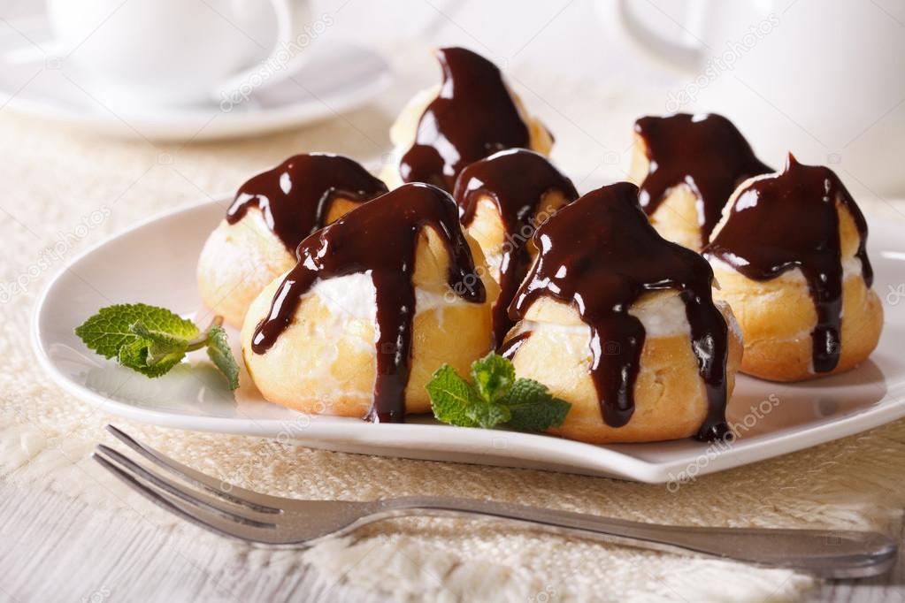 eclairs with cream and chocolate frosting on a plate. horizontal