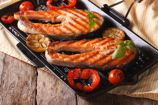 Two salmon steak and vegetables on the grill, horizontal
