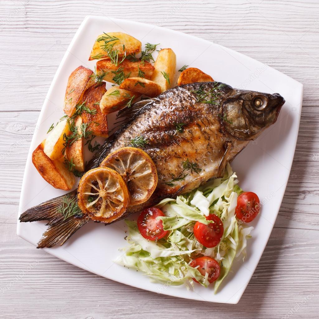 grilled fish with fried potatoes and salad top view, closeup