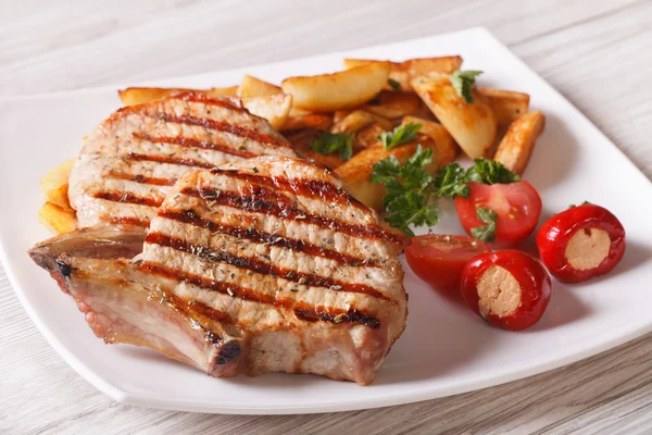 Bistecca di maiale alla griglia con patate e verdure su un piatto — Foto Stock