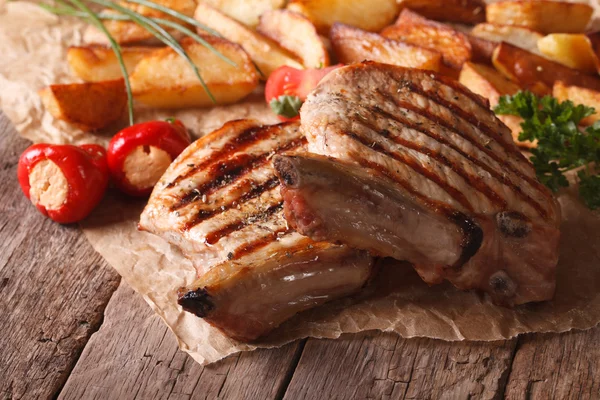 Bife de porco grelhado com batatas e legumes perto do pape — Fotografia de Stock