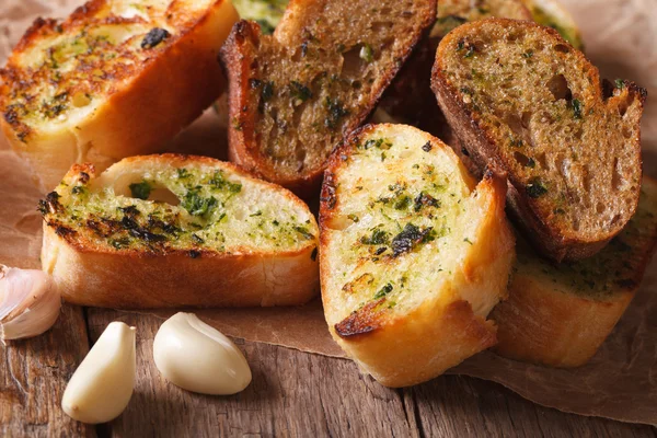 Toasted bread with herbs and garlic closeup on paper. horizontal — Stock Photo, Image