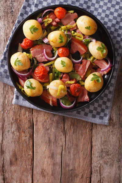 Rustic food: new potatoes, onions, tomatoes and bacon top view — Stock Photo, Image